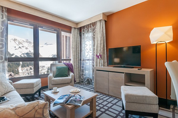 Image of the living area in an apartment within Les Terrasses d'Helios featuring sofa, chair, coffee table, and tv
