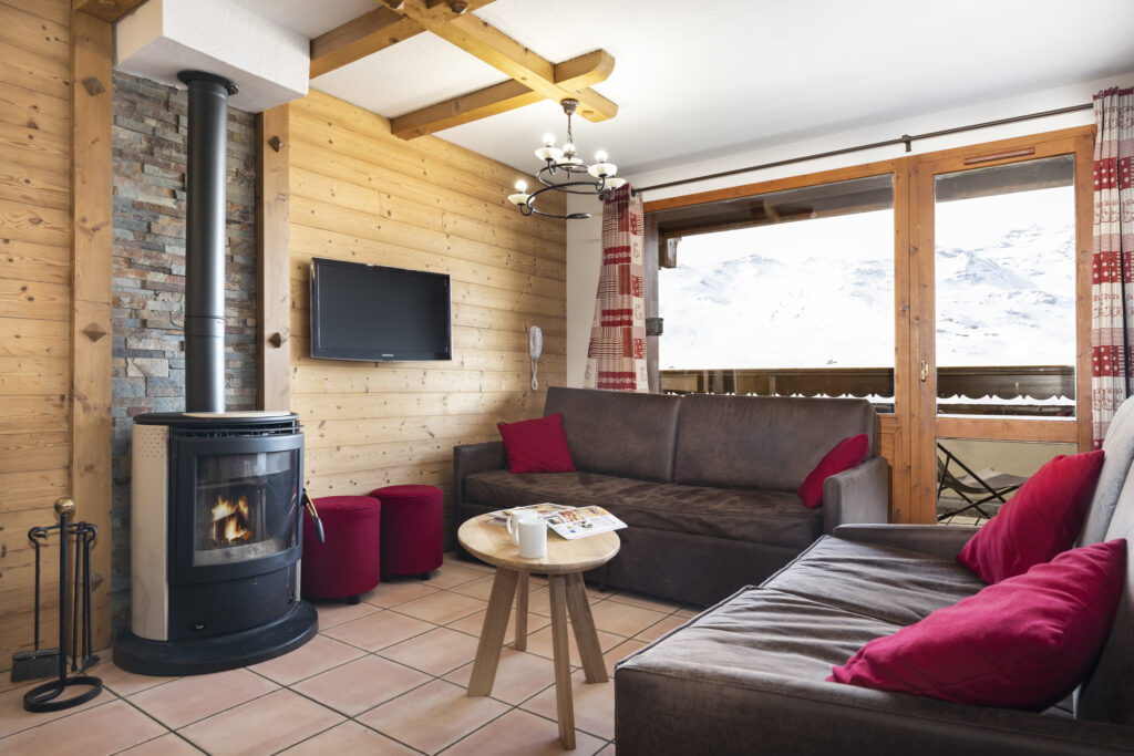 Image of the living area in an apartment in Les Balcons de Val Thorens featuring sofas, TV and a wood burner